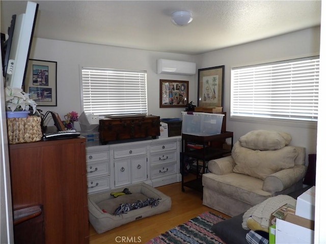 living area with a wall unit AC and light wood finished floors