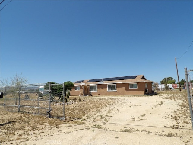 view of front of house featuring roof mounted solar panels and fence