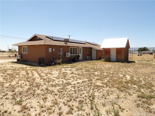 back of house with solar panels, an outdoor structure, fence, and a shed