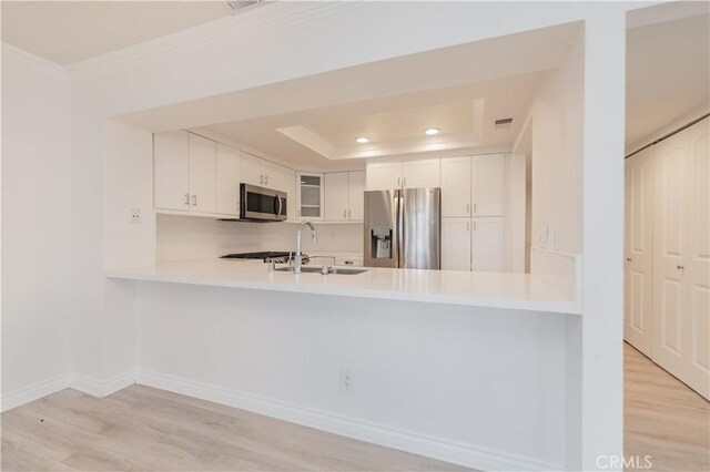 61 Greenfield Unit 68, Irvine, CA 92614 - kitchen with appliances with stainless steel finishes, ornamental molding, a peninsula, a sink, and light wood-style flooring