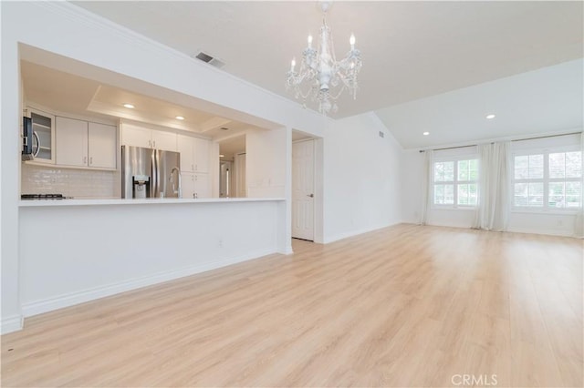 61 Greenfield Unit 68, Irvine, CA 92614 - unfurnished living room with a chandelier, light wood-style floors, recessed lighting, a tray ceiling, and baseboards