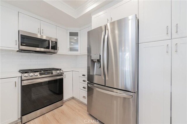 61 Greenfield Unit 68, Irvine, CA 92614 - kitchen featuring stainless steel appliances, ornamental molding, light countertops, white cabinetry, and tasteful backsplash