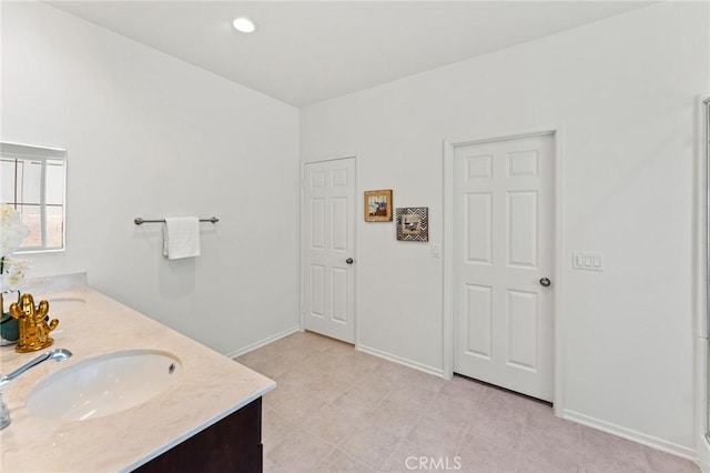 bathroom with double vanity and baseboards