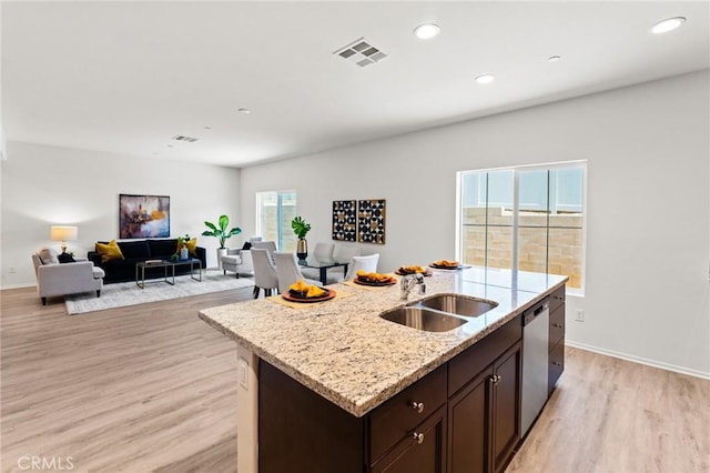 kitchen featuring a sink, light wood-style floors, stainless steel dishwasher, dark brown cabinets, and open floor plan