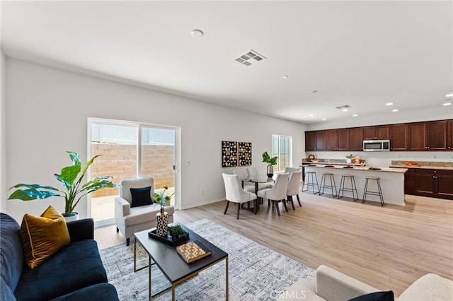 living room with recessed lighting, light wood-style floors, and baseboards