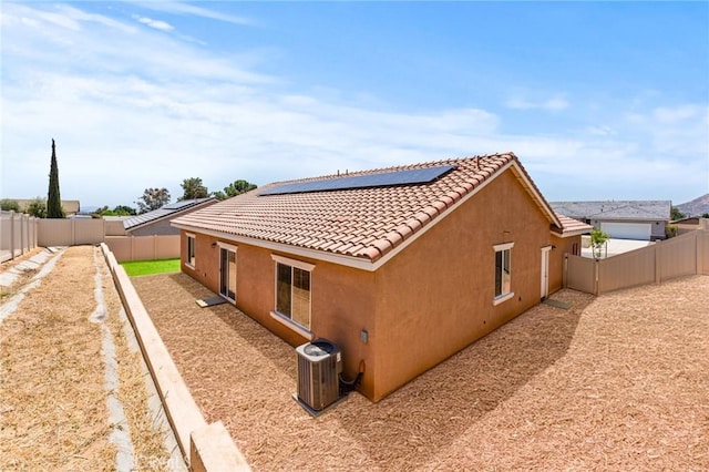 view of home's exterior with stucco siding, solar panels, a fenced backyard, central air condition unit, and a tile roof