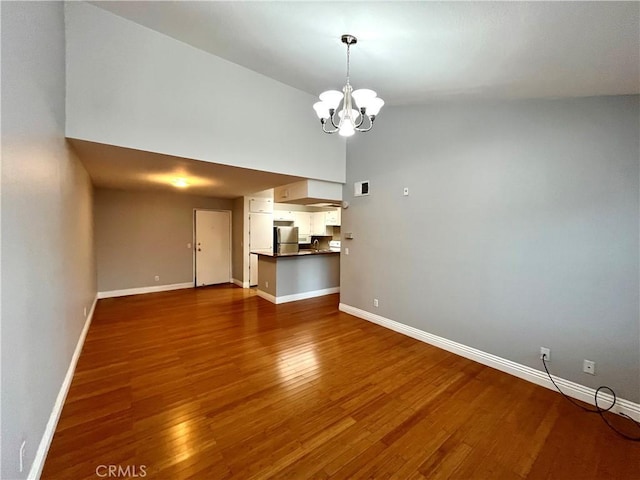 15000 Downey Ave Unit 204, Paramount, CA 90723 - unfurnished living room featuring dark wood finished floors, baseboards, and a chandelier