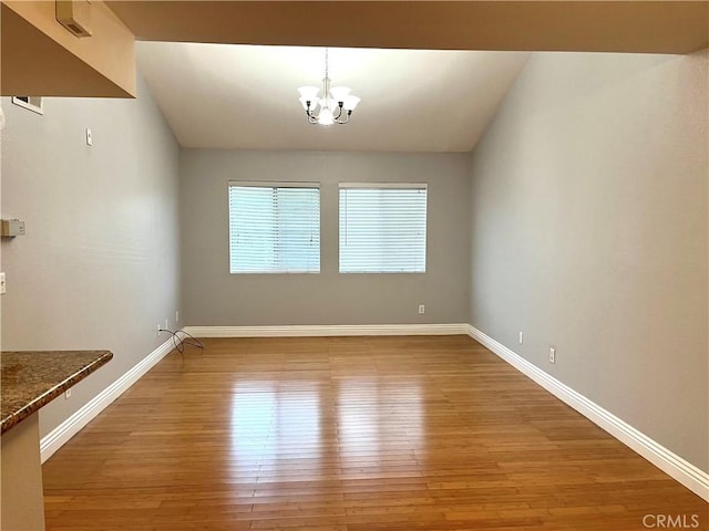 15000 Downey Ave Unit 204, Paramount, CA 90723 - unfurnished dining area featuring light wood finished floors, a chandelier, and baseboards