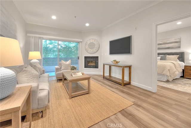 living area featuring crown molding, wood finished floors, baseboards, recessed lighting, and a fireplace