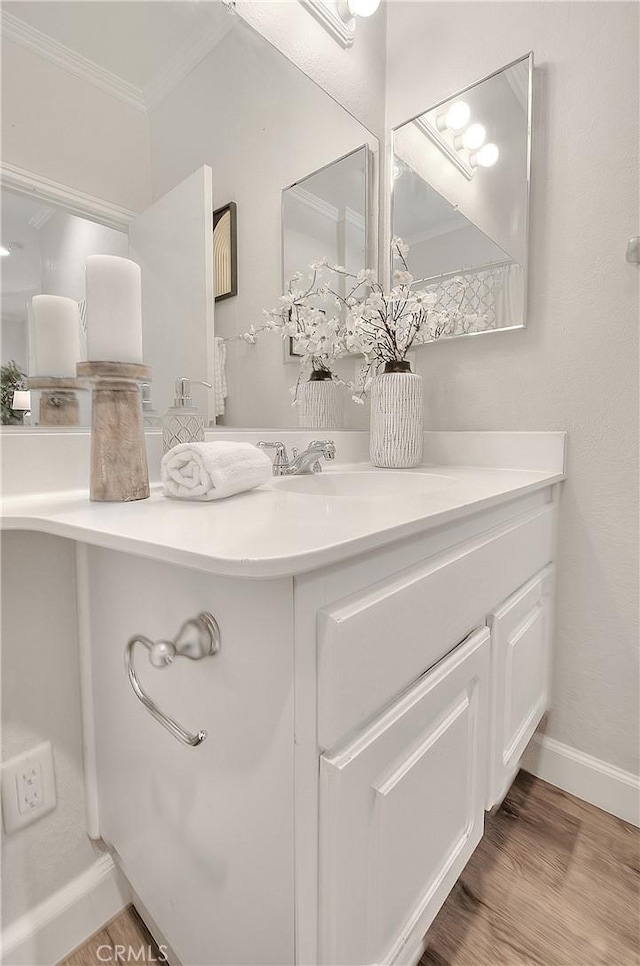 bathroom with crown molding, wood finished floors, vanity, and baseboards