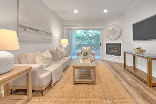 living room featuring crown molding, light wood-type flooring, a fireplace, recessed lighting, and baseboards