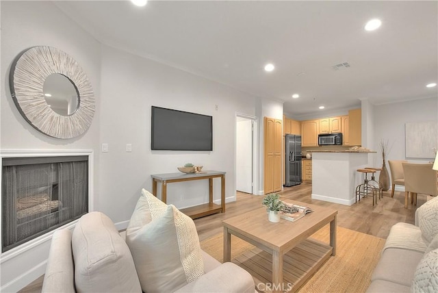 living area featuring recessed lighting, baseboards, light wood-style floors, and a fireplace