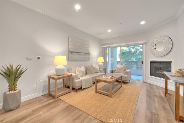 living room with wood finished floors, baseboards, ornamental molding, recessed lighting, and a fireplace