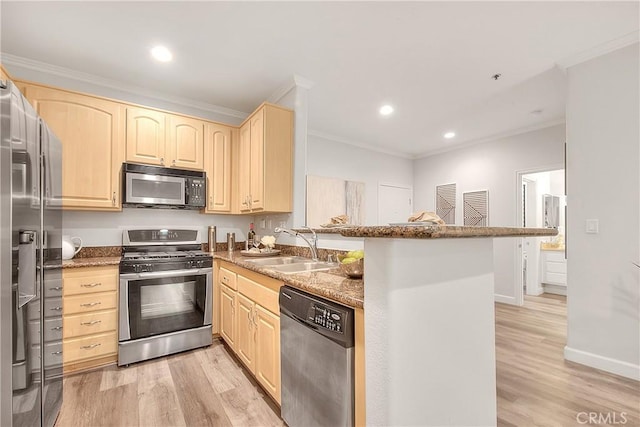 kitchen featuring appliances with stainless steel finishes, light brown cabinets, crown molding, a sink, and a peninsula