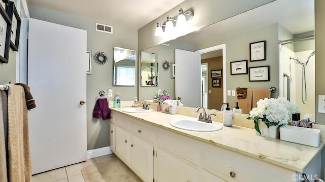 bathroom featuring tile patterned floors, a shower, double vanity, and baseboards