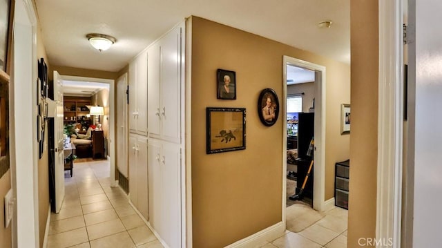hall featuring light tile patterned floors and baseboards