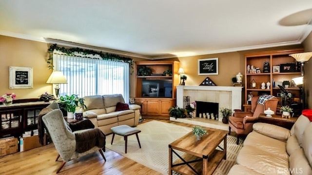 living area with crown molding, light wood finished floors, and a tiled fireplace