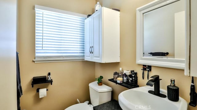 half bathroom featuring a sink, plenty of natural light, and toilet
