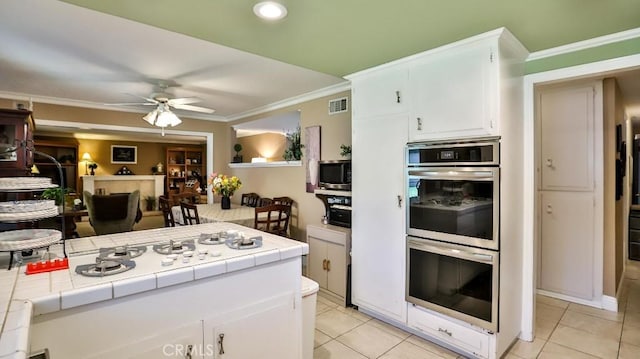 kitchen with stainless steel appliances, tile countertops, light tile patterned flooring, and ornamental molding