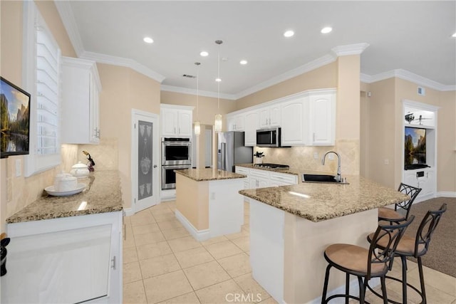 kitchen featuring a sink, appliances with stainless steel finishes, a peninsula, light stone counters, and a kitchen breakfast bar