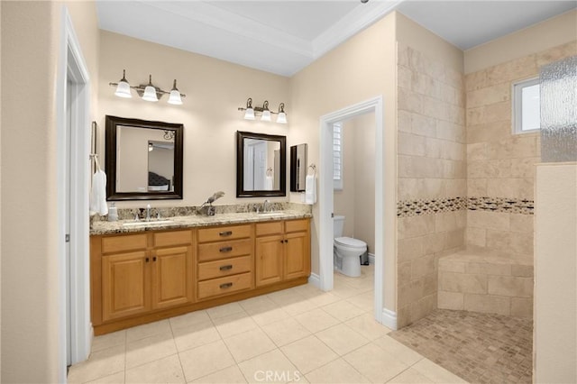 bathroom featuring tile patterned flooring, toilet, double vanity, and tiled shower