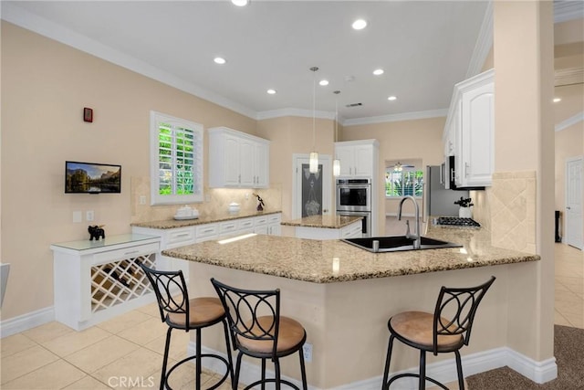 kitchen featuring a sink, a peninsula, tasteful backsplash, healthy amount of natural light, and ornamental molding