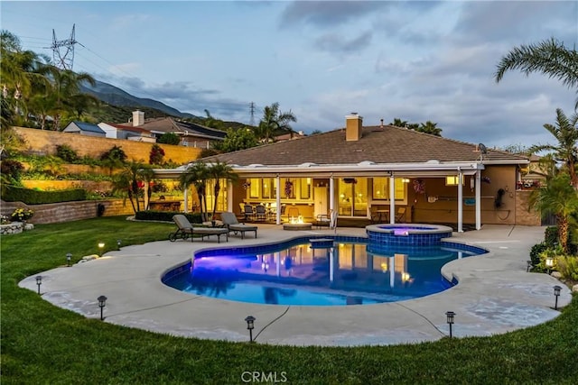 view of swimming pool featuring a patio area, a yard, a mountain view, and a pool with connected hot tub