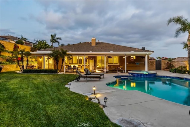 back of property with a patio, a chimney, a pool with connected hot tub, and an outdoor hangout area