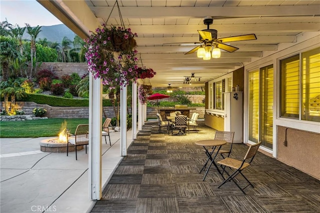 view of patio with a fire pit, a ceiling fan, a mountain view, and outdoor dining area