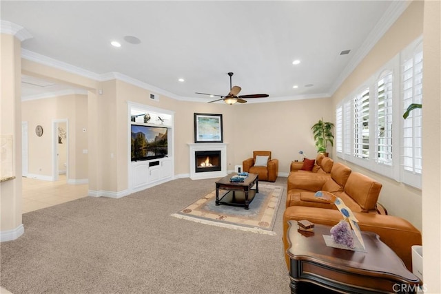 carpeted living room with ceiling fan, recessed lighting, crown molding, a warm lit fireplace, and baseboards