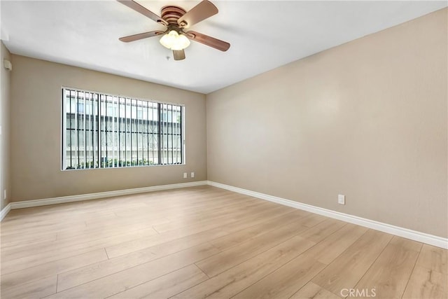 spare room with baseboards, light wood-type flooring, and ceiling fan
