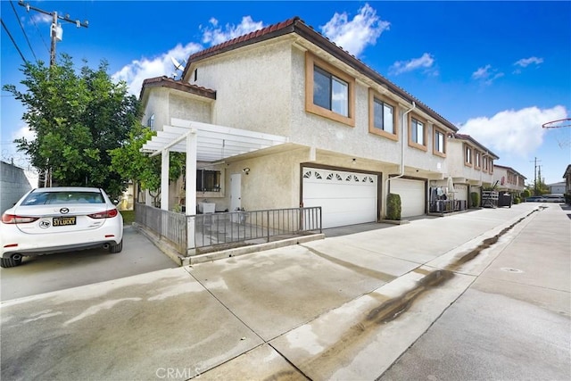 view of front of house featuring a garage, concrete driveway, stucco siding, a residential view, and a tiled roof