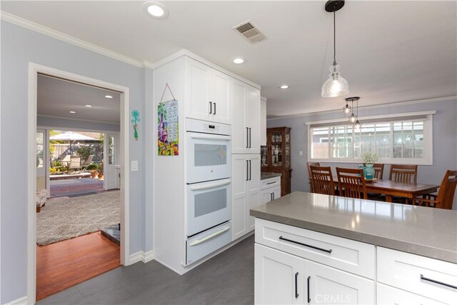 2952 Pemba Dr, Costa Mesa, CA 92626 - kitchen with a warming drawer, white double oven, ornamental molding, hanging light fixtures, and white cabinetry