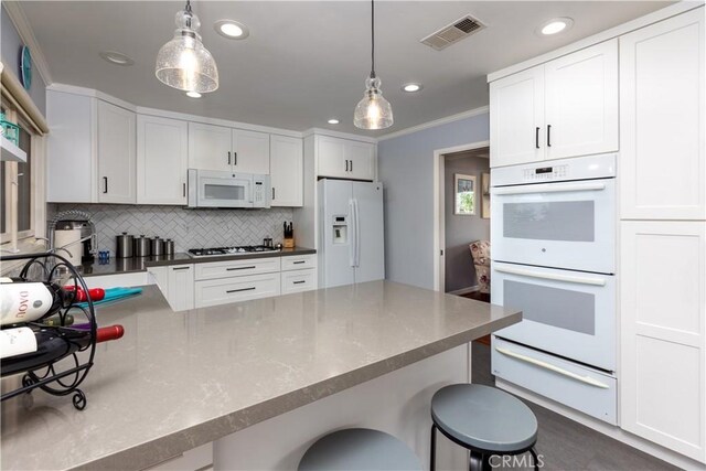 2952 Pemba Dr, Costa Mesa, CA 92626 - kitchen with white appliances, a warming drawer, recessed lighting, a breakfast bar, and crown molding