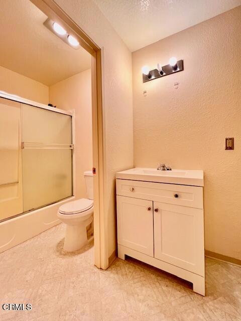 511 Cypress St Unit 4, Fort Bragg, CA 95437 - full bathroom with a textured wall, toilet, bath / shower combo with glass door, and vanity