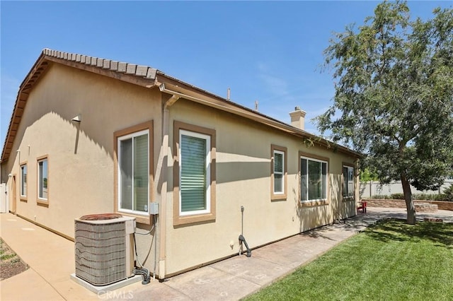 1704 Golden Way, Beaumont, CA 92223 - view of home's exterior with central air condition unit, stucco siding, a chimney, and a patio area