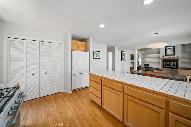 2350 Meadow St, San Luis Obispo, CA 93401 - kitchen featuring freestanding refrigerator, tile counters, high end stainless steel range oven, open floor plan, and light wood-type flooring