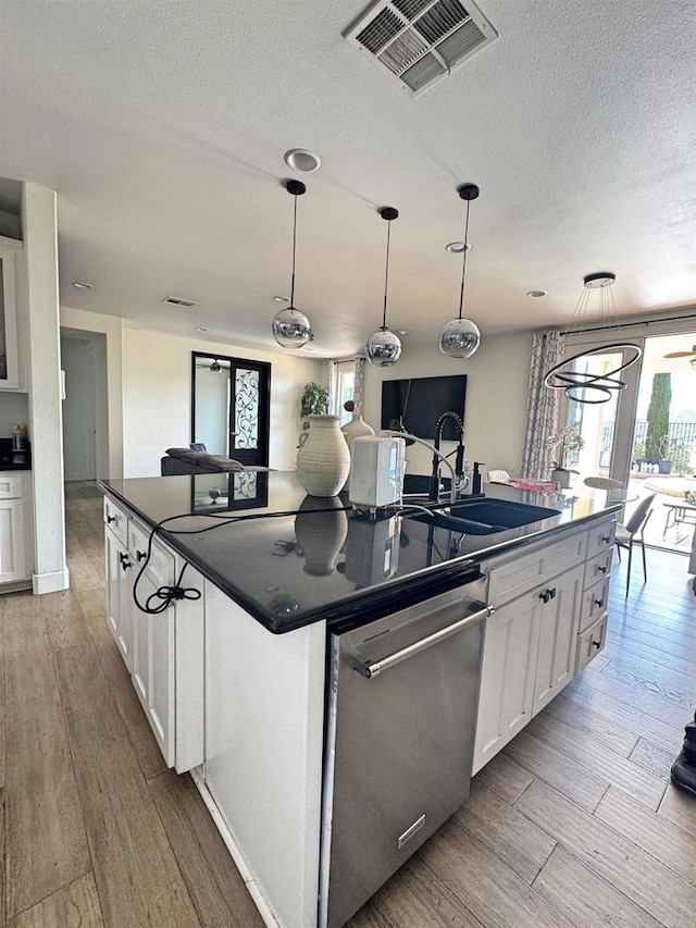 1498 Berry Creek Pl, Chula Vista, CA 91913 - kitchen with dark countertops, dishwasher, a sink, an island with sink, and white cabinetry