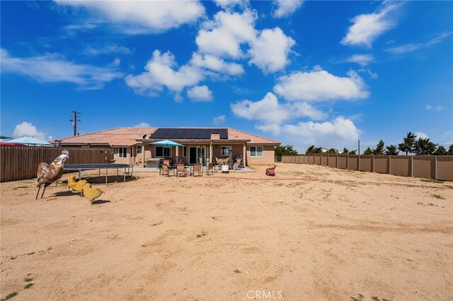 10779 Mills Rd, Apple Valley, CA 92308 - back of property with a trampoline, a patio, roof mounted solar panels, and a fenced backyard
