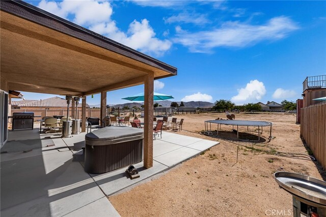10779 Mills Rd, Apple Valley, CA 92308 - fenced backyard featuring a trampoline, a patio, a hot tub, and a mountain view