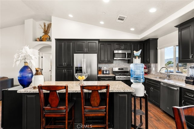 10779 Mills Rd, Apple Valley, CA 92308 - kitchen with appliances with stainless steel finishes, a sink, dark cabinetry, vaulted ceiling, and tasteful backsplash