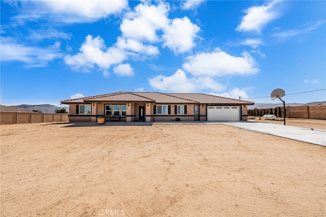 10779 Mills Rd, Apple Valley, CA 92308 - view of front of property featuring a tile roof, a garage, driveway, stucco siding, and a mountain view