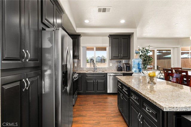 10779 Mills Rd, Apple Valley, CA 92308 - kitchen with appliances with stainless steel finishes, dark cabinetry, a kitchen island, backsplash, and dark wood-style floors