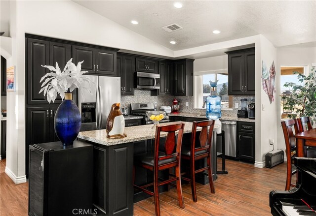 10779 Mills Rd, Apple Valley, CA 92308 - kitchen with appliances with stainless steel finishes, dark cabinets, a center island, wood finished floors, and lofted ceiling