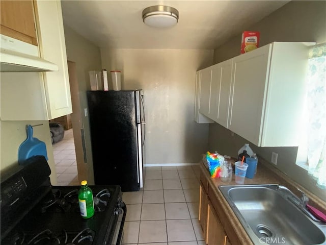 215 W 23rd St, San Bernardino, CA 92405 - kitchen featuring black gas range oven, freestanding refrigerator, light tile patterned floors, under cabinet range hood, and white cabinetry