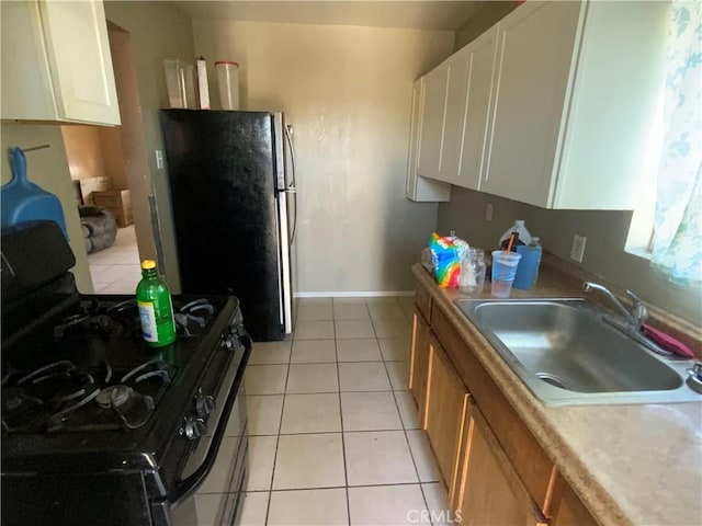 215 W 23rd St, San Bernardino, CA 92405 - kitchen featuring black gas range oven, freestanding refrigerator, white cabinets, light tile patterned flooring, and light countertops