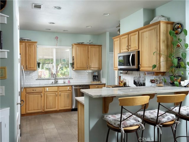 1417 23rd St, Oceano, CA 93445 - kitchen with a sink, stainless steel appliances, a peninsula, a breakfast bar area, and backsplash