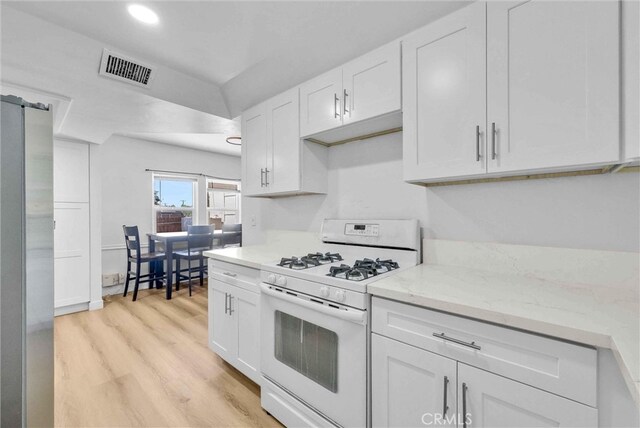 2513 Genevieve St, San Bernardino, CA 92405 - kitchen featuring white range with gas cooktop, freestanding refrigerator, white cabinets, light wood-style floors, and light stone counters