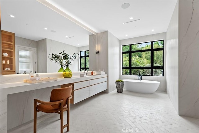 full bath with a freestanding bath, double vanity, and recessed lighting
