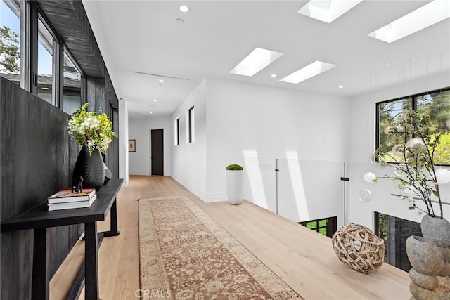 hallway with a skylight, light wood-style floors, and recessed lighting